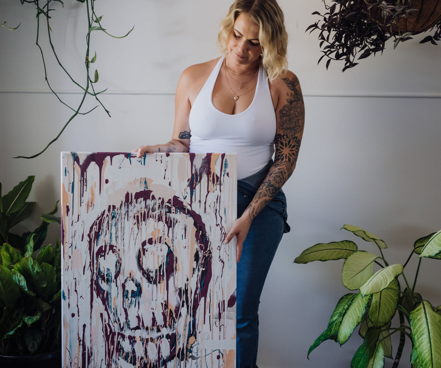 Artist holding an original abstract skull painting in her studio.