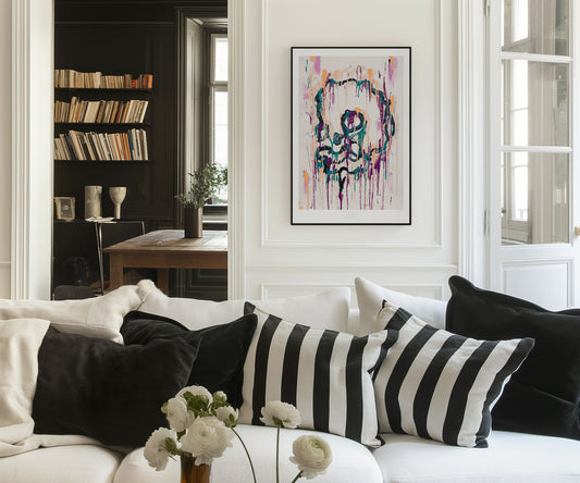 Framed abstract skull art print by The Jana Saga displayed on a wall above a sofa in a modern living room.