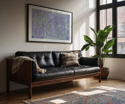 Framed purple abstract wall art print by The Jana Saga hanging above a leather sofa in a modern living room.